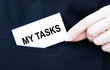 © Veranika - Business concept. The businessman puts a business card with the inscription MY TASKS in his jacket pocket.