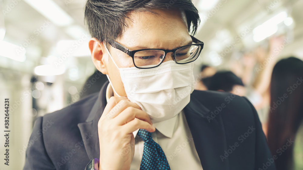 Young man wearing face mask travels on crowded subway train . Coronavirus disease or COVID 19 pandemic outbreak and urban lifestyle problem in rush hour concept . - obrazy, fototapety, plakaty 