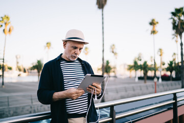 Concentrated elderly man using tablet on street