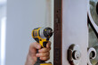 © ungvar - Locksmith hand holds the screwdriver in installing new house door lock