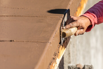 Wall Mural - Construction Worker Using Wood Trowel On Wet Cement Forming Coping Around New Pool