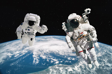 Wall Mural - two astronauts walking in space with earth background. elements of this image furnished by nasa