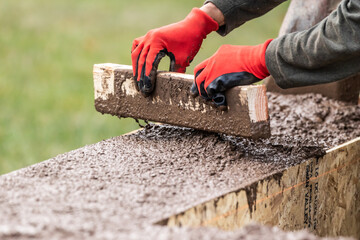 Wall Mural - Construction Worker Leveling Wet Cement Into Wood Framing