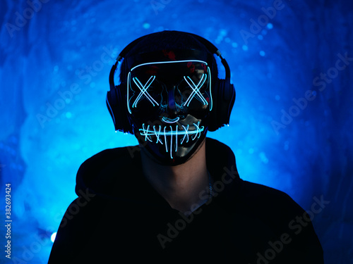 Fotomural Portrait of a guy with headphones and a glowing Halloween mask