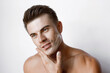 © KDdesignphoto - Muscular sexy model sports young man on white background. Portrait of beautiful smiling healthy guy applying foam for washing on his face. Facial skincare routine.