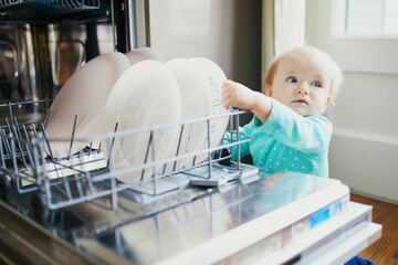 Wall Mural - Little child helping to unload dishwasher