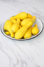 Fresh Yellow Summer Squash In A White Bowl On A Marble Countertop