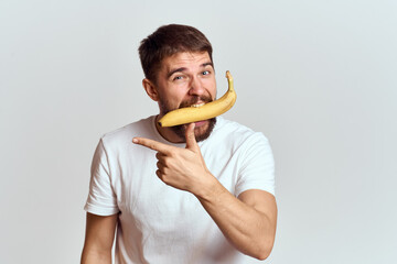 Cheerful man with a banana in his hands on a light background fun emotions Cropped view Copy Space