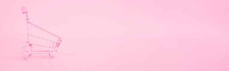 shopping and payment concept from small trolley on pink pastel color background. web banner size.