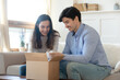 © fizkes - Wow! Excited curious millennial spouses husband and wife opening unpacking awaited parcel with interest and pleasure, glad happy young family receiving order or delivery from internet shop by mail