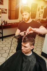 Hairdresser at work. Drying young man's hair in a barber shop