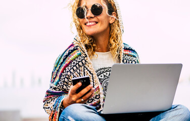 Portrait of cheerful adult caucasian woman working outdoor with phone and laptop computer in roaming technology - free from office lifestyle modern people concept