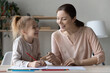 © fizkes - Happy young mother and little girl having fun, drawing colored pencils, pretty adorable daughter with smiling mum enjoying leisure time, creative activity together, sitting at desk at home
