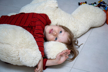 Unhappy Child boy lies on the floor at home or in kindergarten among toys and is sad or falls asleep. Social concept of childhood loneliness, illness and sadness. Adaptation to kindergarten