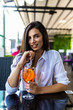 © F8  \ Suport Ukraine - Young pretty smiling woman holding the glass of Aperol Spritz cocktail in cafe