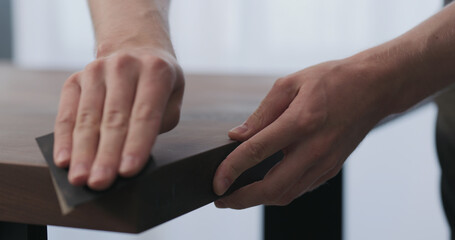 Sticker - man hand sanding toned walnut table surface before applying finish
