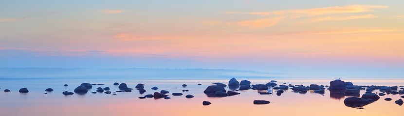 rocks at the coast of kasmu (captain's village) at sunset. estonia, baltic sea. clear blue sky, pink