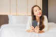 © siraphol - Portrait beautiful young asian woman use smart mobile phone on bed