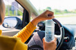 © sorapop - Asian woman holding a water bottle for drink while driving the car in the morning during going to work on highway road, Transportation and vehicle concept