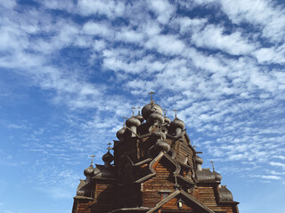 Wooden orthodox church domes in the blue sky with clouds