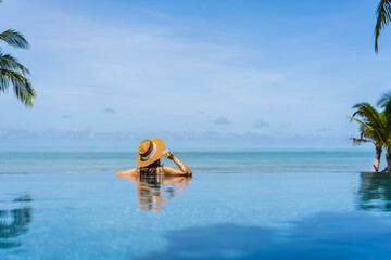 Young woman traveler relaxing and enjoying by a tropical resort pool while traveling for summer vacation, Travel concept