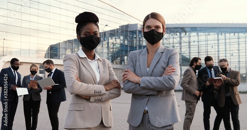 Fotografía Portrait mixed-races young businesswomen in masks and official style standing posing to camera outdoor in city