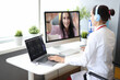 © H_Ko - Female doctor in white coat and headphones conduct online consultation. Woman sit at table and work at laptop and computer.