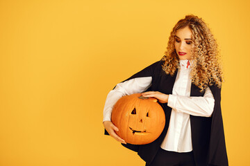 Wall Mural - Woman wearing black costume. Lady with halloween makeup. Girl standing on a yellow background.
