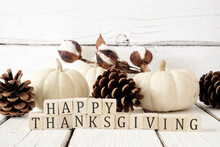 Happy Thanksgiving Greeting On Wooden Blocks Against A White Wood Background With White Pumpkins And Brown Autumn Decor