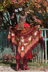 Red fall leaves in Borovsk city, Russia. Girl in vintage red Pavlovo Posad shawl. Russian village, autumn nature in countryside, folk style in fashion. Pavlovoposadsky shawl, scarf. Fall garden