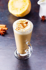 pumpkin spice latte, coffee maker and milk jug on a dark background. pumpkin latte with whipped crea