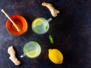 Wall Mural - Ginger tea with lemon on a dark background. Two cups of ginger tea and ingredients for its preparation