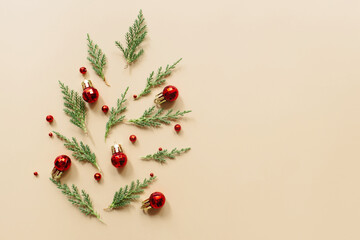 Trendy creatiove Christmas, winter, new year composition. Fir tree branches, red decorations on beige background. Flat lay, top view, copy space