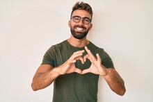 Young Hispanic Man Wearing Casual Clothes And Glasses Smiling In Love Showing Heart Symbol And Shape With Hands. Romantic Concept.