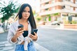 © Krakenimages.com - Young hispanic girl with serious expression using smartphone and drinking take away coffee at the city.