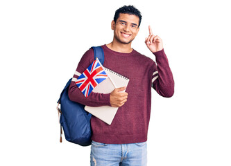 Wall Mural - Hispanic handsome young man exchange student holding uk flag surprised with an idea or question pointing finger with happy face, number one