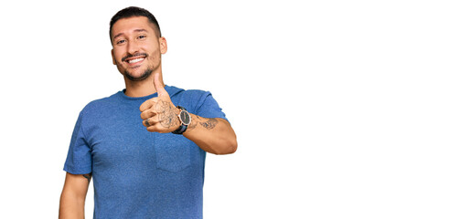 Handsome man with tattoos wearing casual clothes doing happy thumbs up gesture with hand. approving expression looking at the camera showing success.