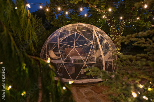 Individual tent igloo with vintage lighting overhead as a place to eat dinner