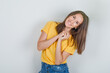 © 8 Photo - Young woman posing like asking for a favor in yellow t-shirt, shorts and looking cheerful , front view.