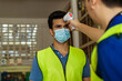 © twinsterphoto - Young Indian factory warehouse worker wearing face mask getting body temperature check with infrared thermometer scanner before working. Security measure at workplace in Coronavirus Covid 19 pandemic
