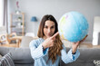 © BestForYou - Woman dreaming about travel, pointing with index finger at globe. Planning vacation.