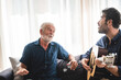 © chokniti - Eldery Father and adult son are playing music and sing a song together. The happy family concept with the guitar instrument.