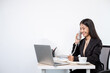 © Orathai - Asian businesswoman talking on the phone and working on a laptop with a cheerful and happy smile while working at the office