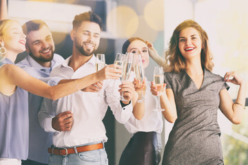 Canvas Print - Young people clinking glasses of tasty champagne at party in office