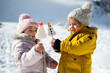 © Halfpoint - Two small children standing in snow in winter nature, eating sweets.