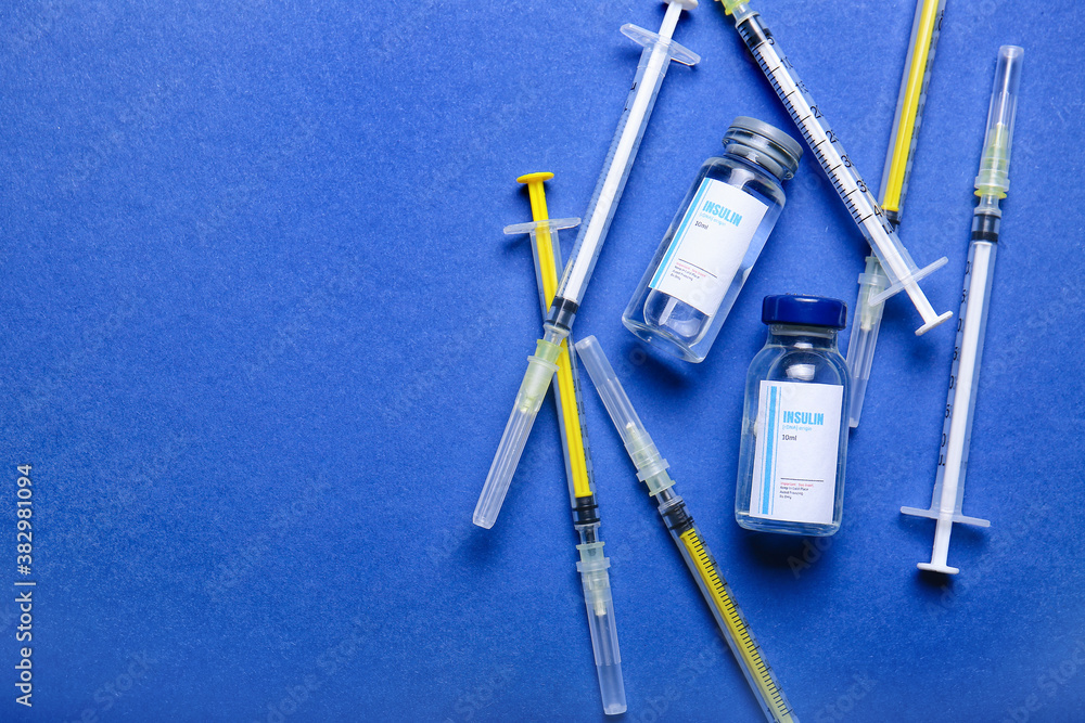 Bottles of insulin with syringes on color background. Diabetes concept