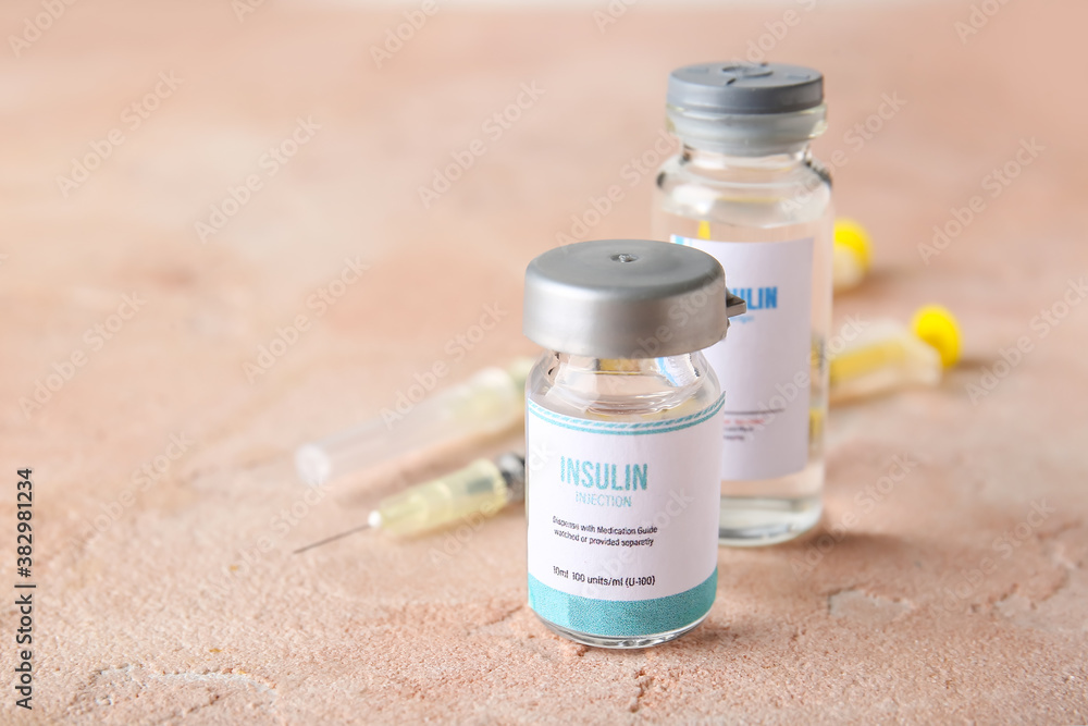 Bottles of insulin with syringes on color background. Diabetes concept
