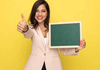 Wall Mural - happy girl in pink suit holding green blackboard and smiling