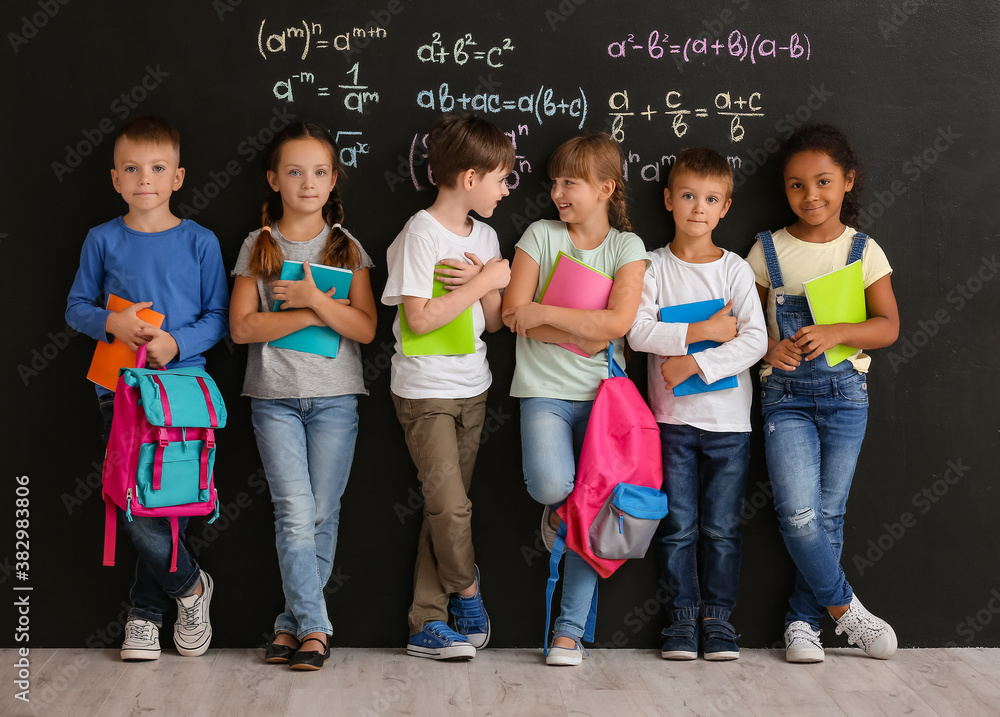 Cute pupils near blackboard in classroom