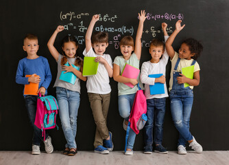 Cute pupils near blackboard in classroom